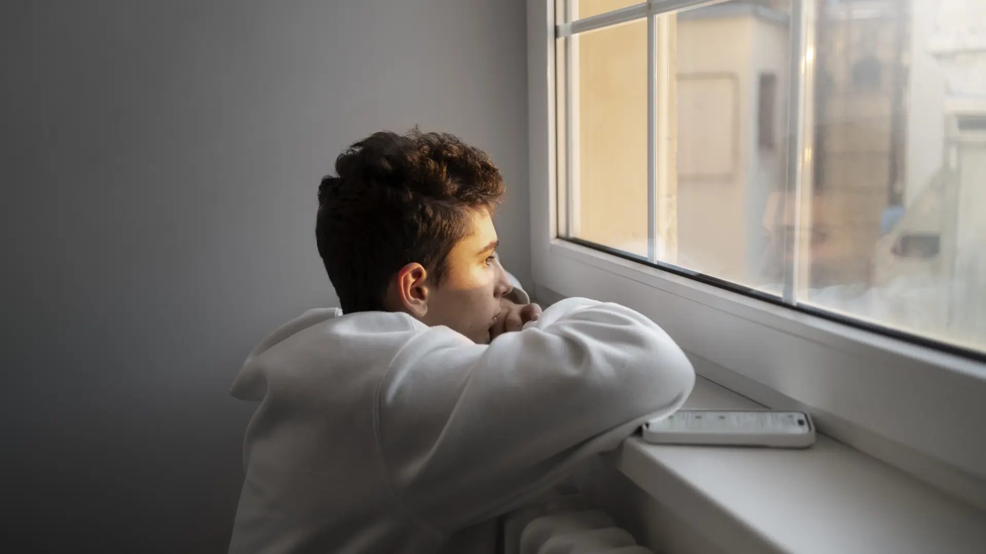 Foto de archivo de un adolescente mirando por la ventana.meteleva/freepik