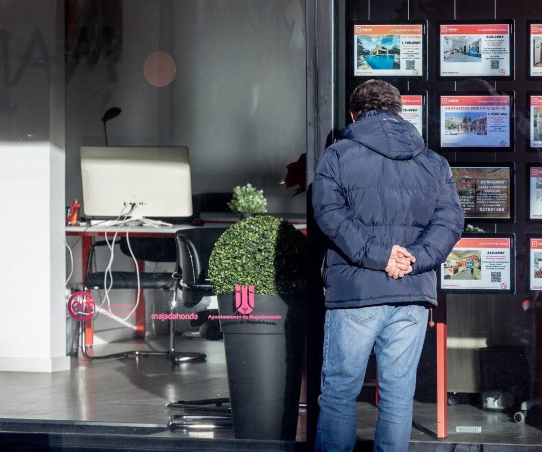 Un hombre observa anuncios de viviendas en venta en el escaparate de una inmobiliaria.EP