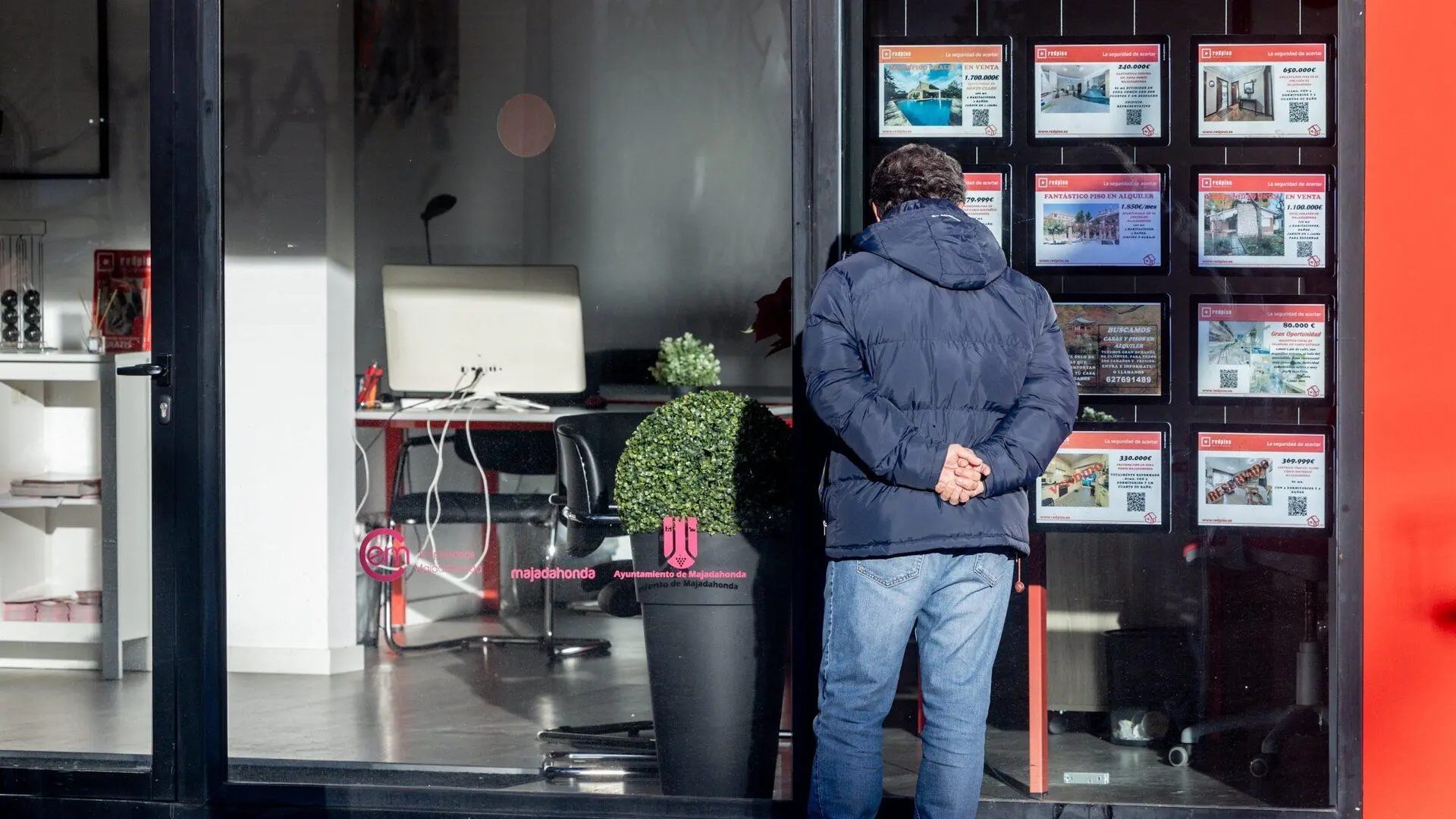 Un hombre observa anuncios de viviendas en venta en el escaparate de una inmobiliaria.EP