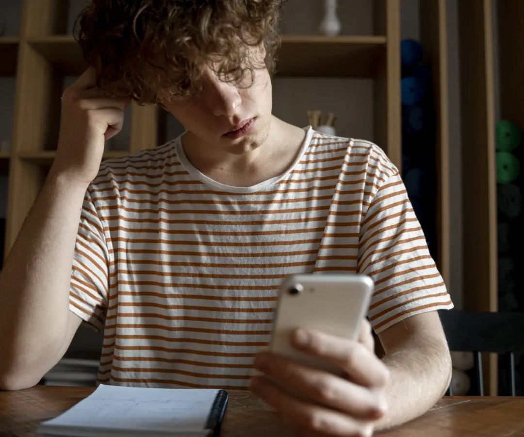 Foto de archivo de un chico joven con su teléfono móvil.Freepik